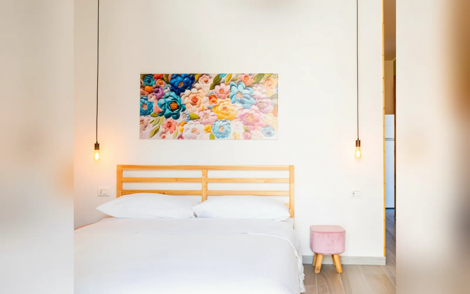 Il letto matrimoniale della Suite Familiare con il quadro di fiori colorati